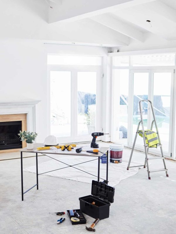 Shot of building plans and equipment on a table in an empty living room during the day.